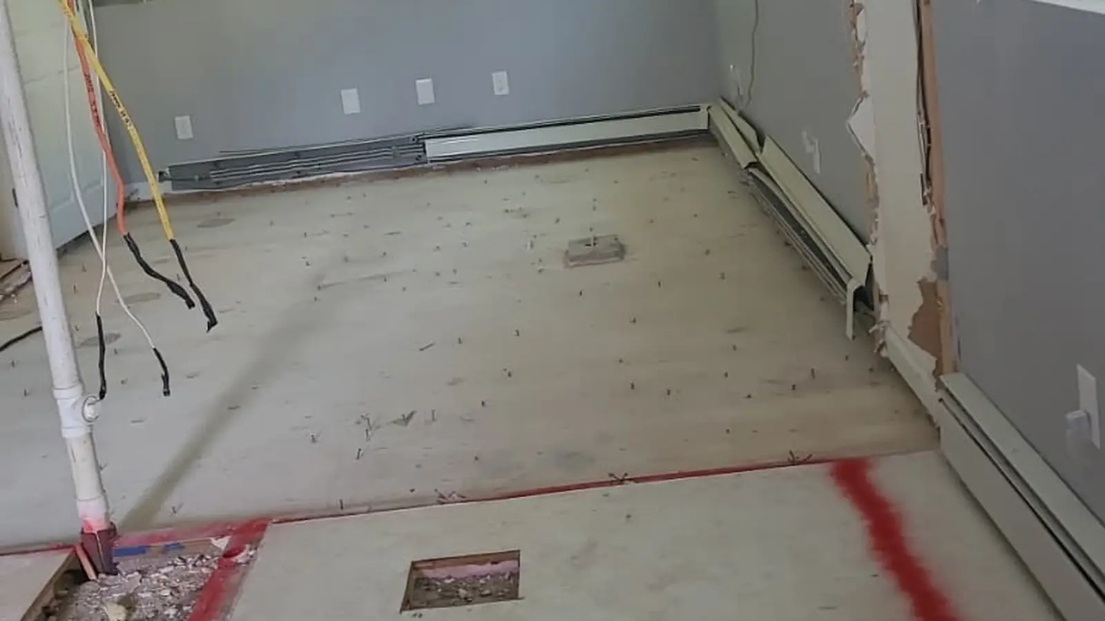 Room stripped during interior demolition, floor marked for new plumbing