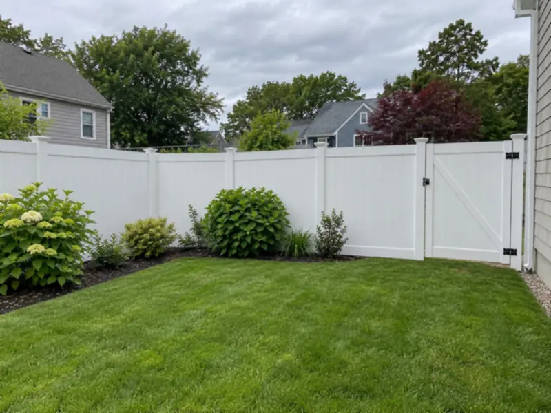 White vinyl privacy fence with a matching gate in a small backyard