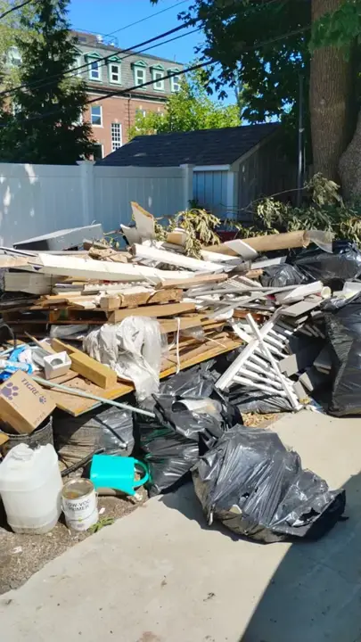 Renovation debris piled beside a white vinyl fence before WA hauled it away