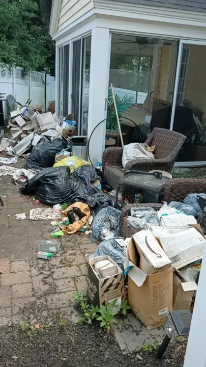 Patio crowded with bags, boxes and worn outdoor chairs before a cleanout